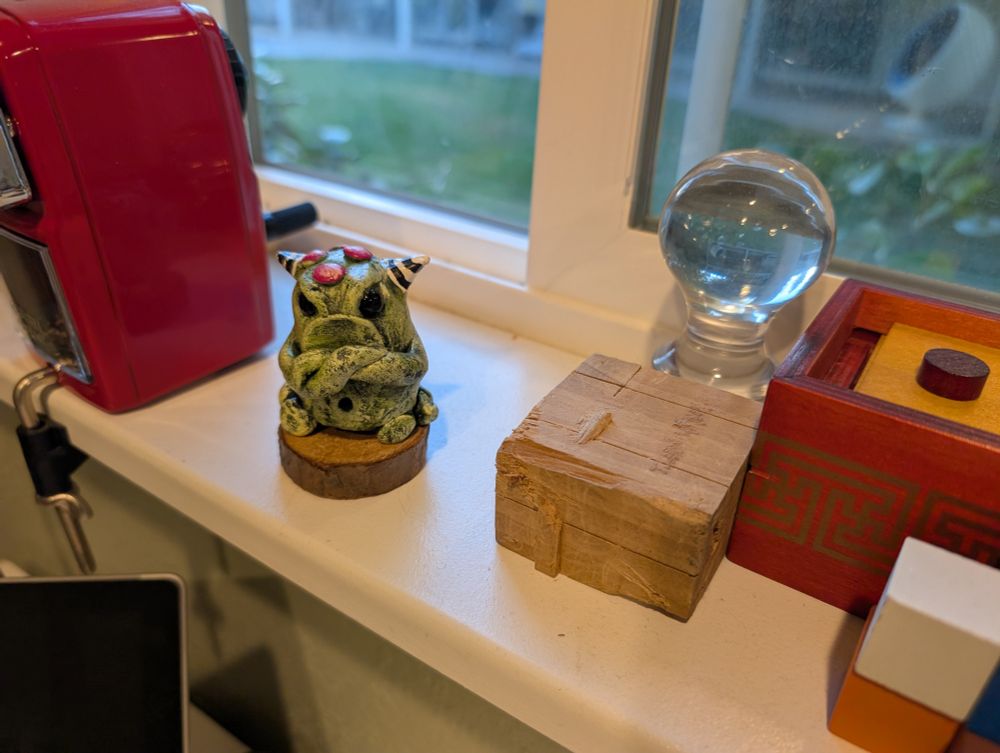 A cute, grumpy, green figurine with folded arms.