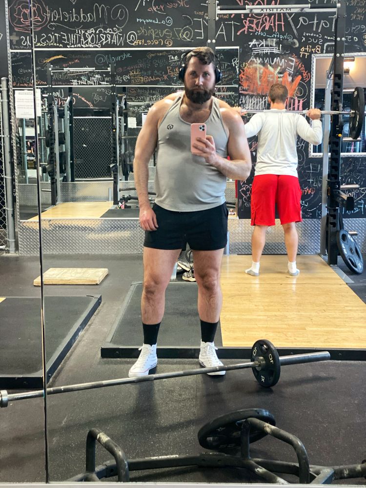 Man posing in the mirror at the gym after his chest workout flexing his muscles.