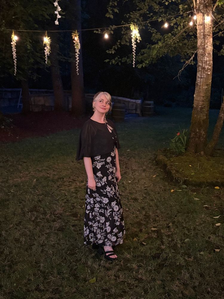 Meowlex outside under fairy lights with flowers hanging from them 