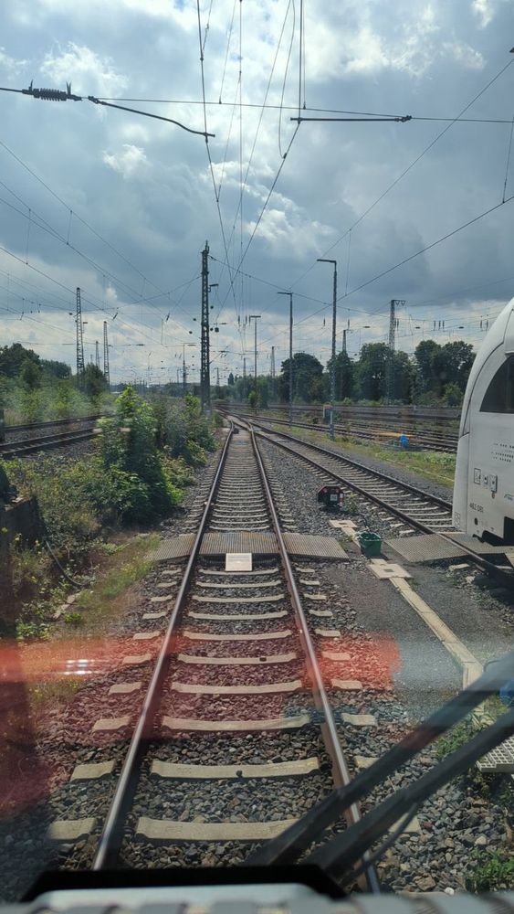 Bild eines Bahnhofes aus der Abstellanlage heraus. Man sieht ein Signal mit zwei roten Leuchten vor einer Weiche stehen.