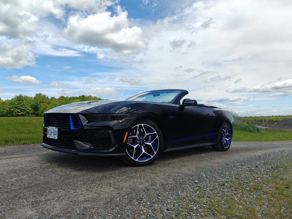 2025 Ford Mustang GT convertible California Special against a green field on a gravel road.