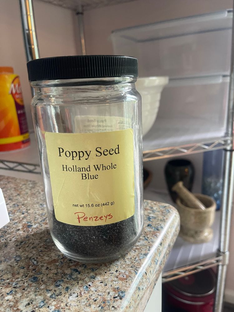 A glass jar that contains Holland Whole Blue Poppy Seed from Penzeys sitting on a kitchen countertop. When I fell in love with the “Lemon-Poppy Seed Waffles” recipe that came with a Cuisinart Waffle Maker, I had to find a place that I could get a bulk supply of poppy seeds at a reasonable price. 