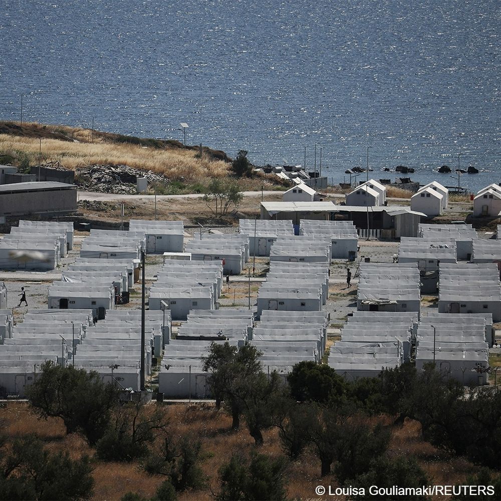 Dozens of small makeshift buildings in a fenced in area near the sea make up the temporary Kara Tepe Refugee Camp in Mavrovouni, Lesbos island, Greece, which was photographed on June 27, 2025