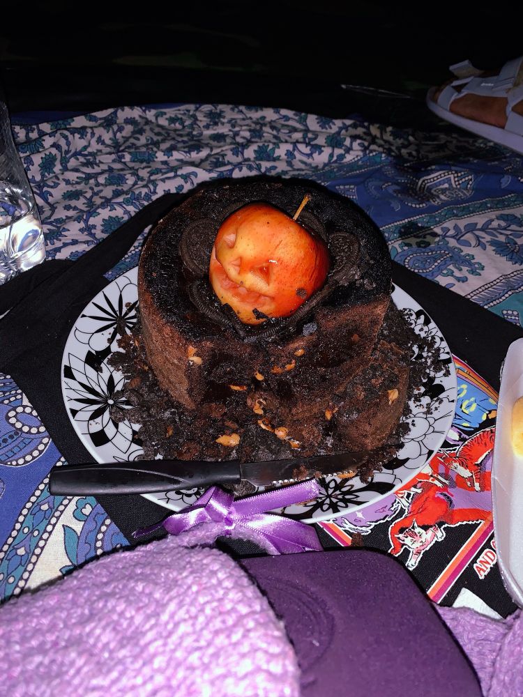 brownie de dois andares com uma maçã do amor em formato de abóbora do halloween em cima, cortado ao meio mostrando seu recheio de amendoins
