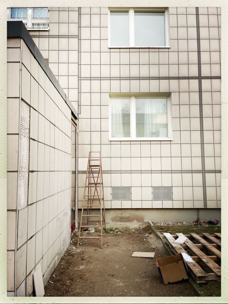 Eine Plattenbaufassade, davor steht eine Leiter