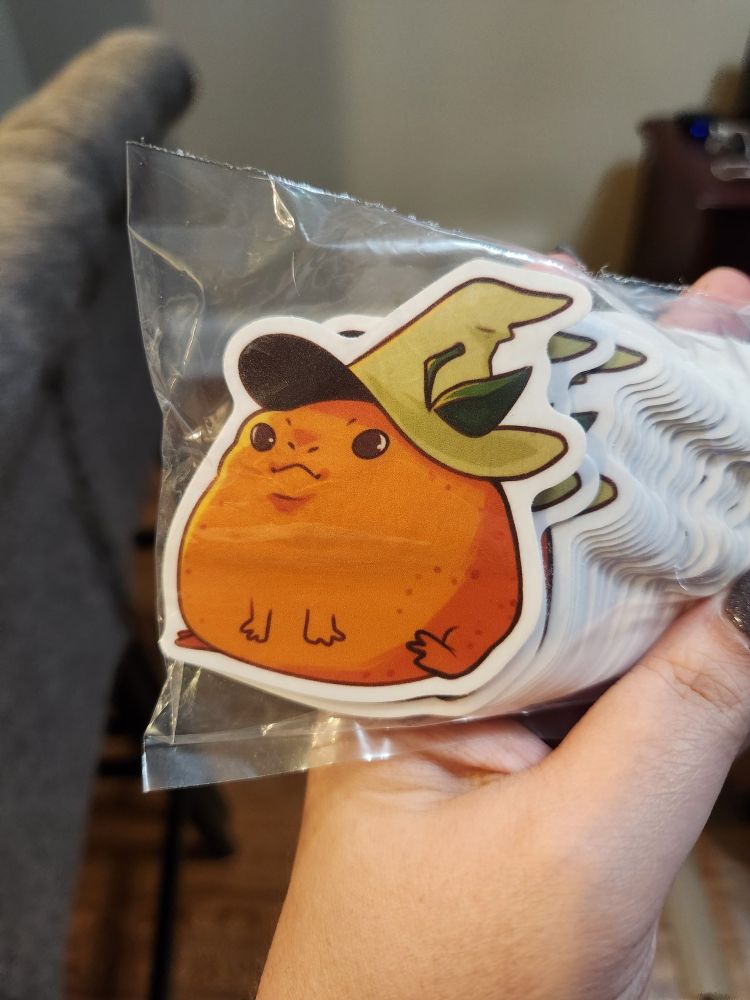 sticker of orange frog with a green witch hat
