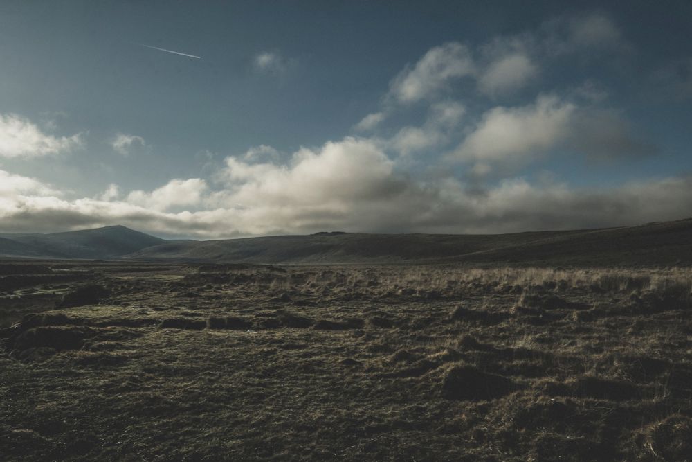 Looking across a valley towards a ridge of low lying hills and tors.