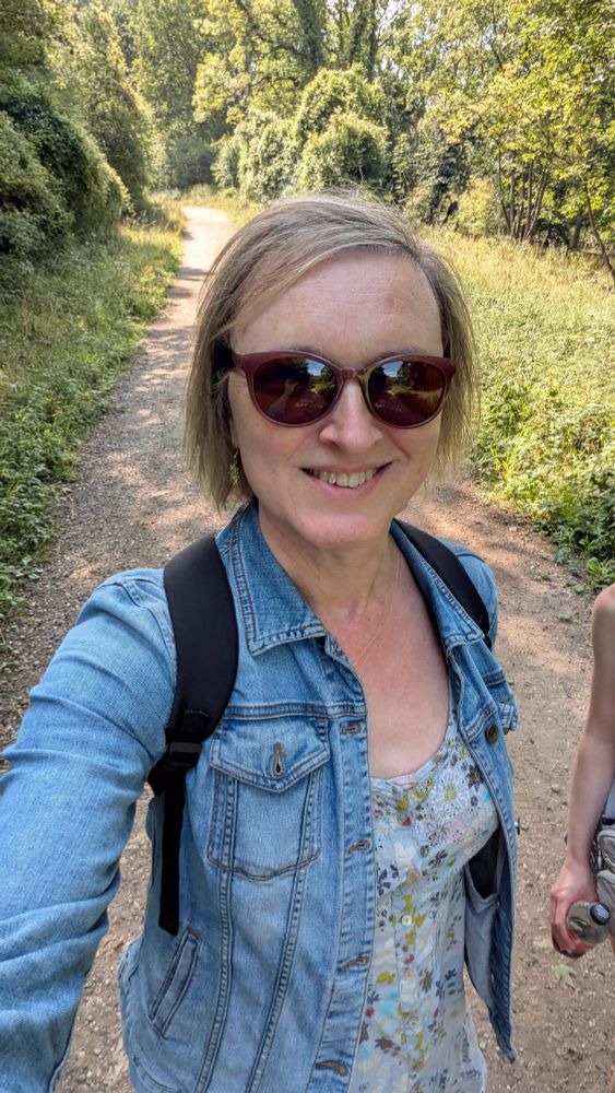 A woman in a denim jacket walking in the woods