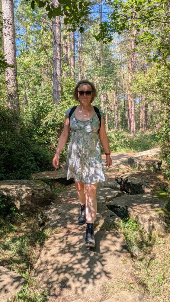 A woman in a blue sundress walking in the woods