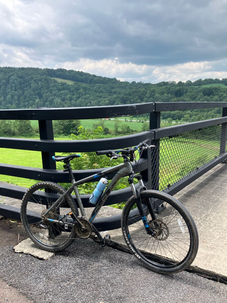 A mountain park parked next to a bike trail with a bucolic view behind it.