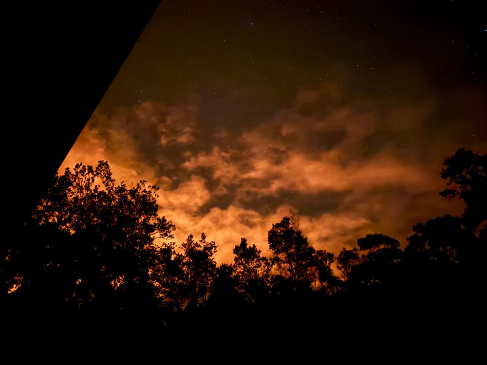A glowing evening sky in orange against a silhouette of trees. 