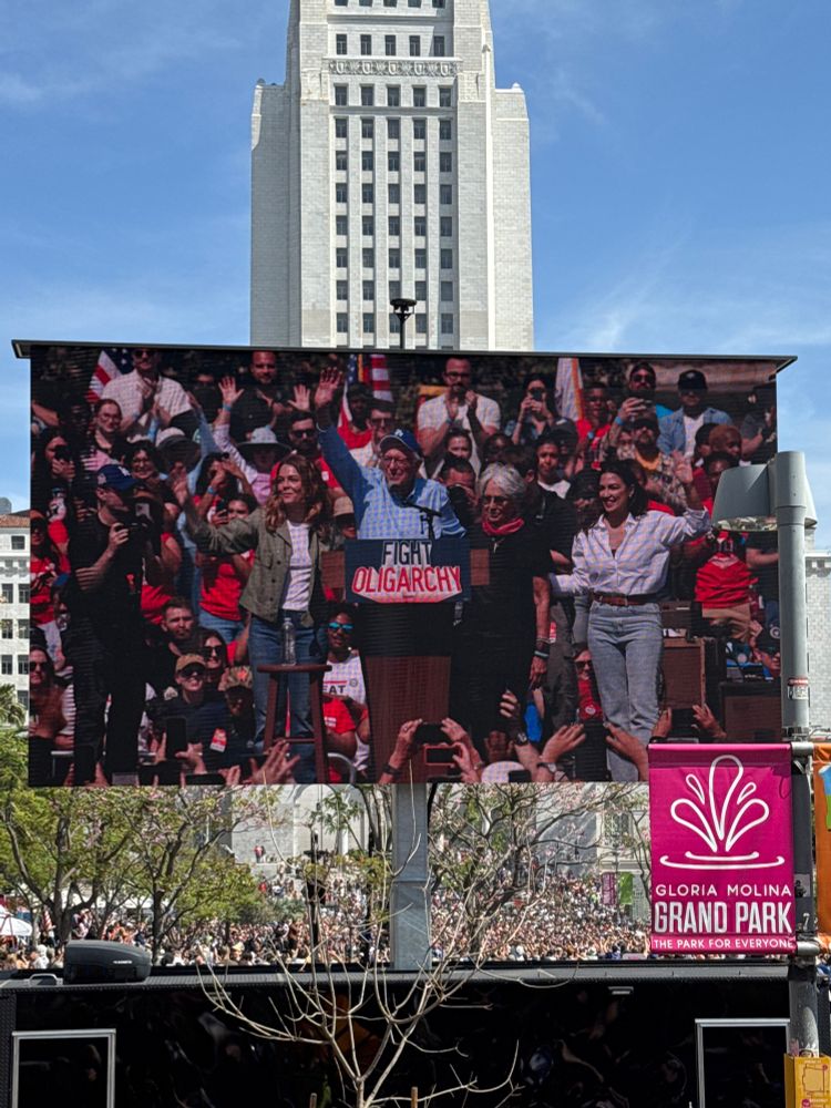 Bernie and AOC waving on the Jumbotron at the rally.