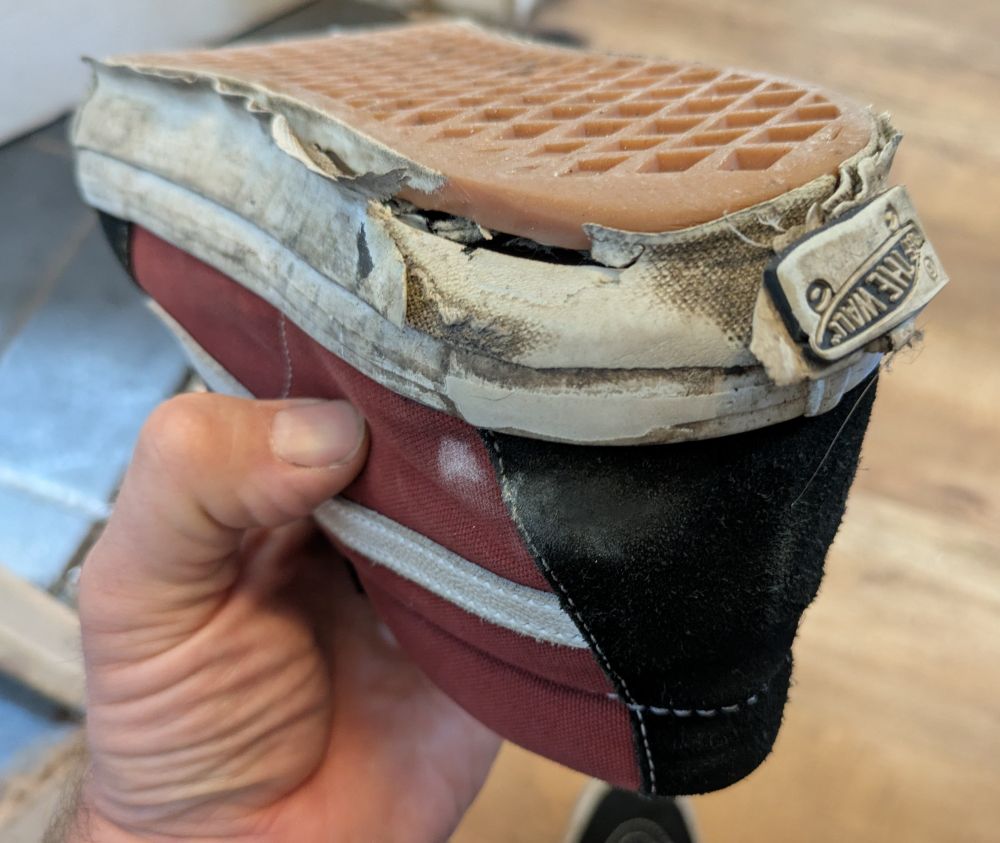 A four month old Vans trainer with the sole peeling off and excessive damage around the heel.