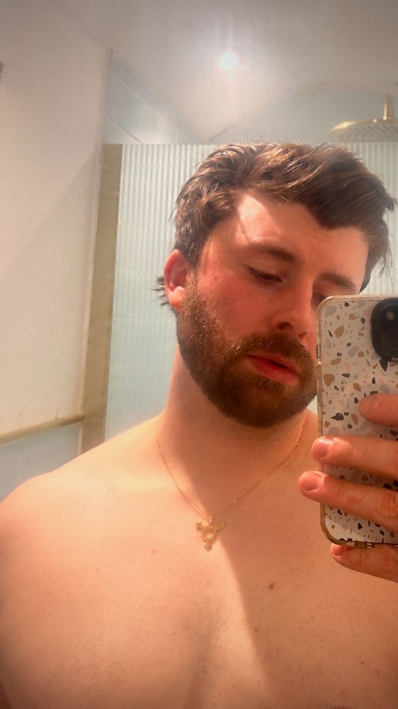 Me wearing a gold necklace with the trans symbol on it. 