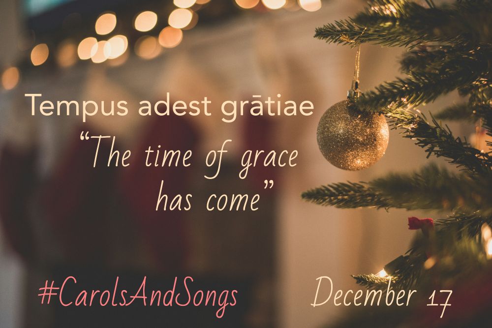 "Tempus adest gratiae"/"The time of grace has come" and #CarolsAndSongs December 17 on a blurred indoor holiday scene