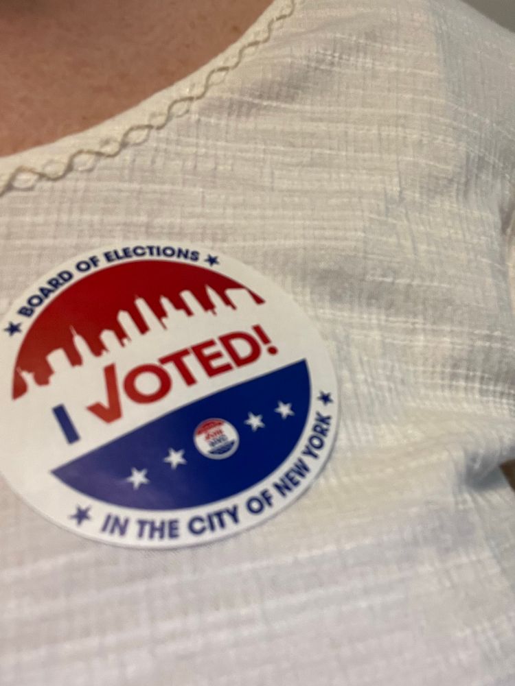 A red, white, and blue “I Voted!” Sticker with an illustration of the nyc skyline. 