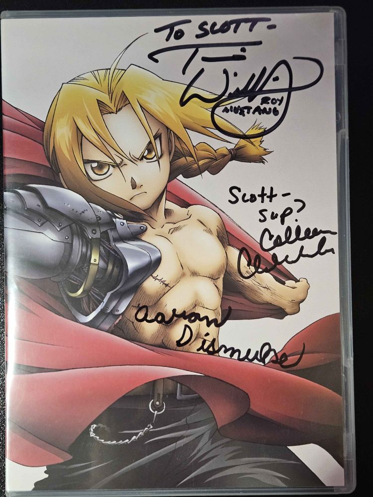 The first DVD of the original "Full Metal Alchemist" signed by Travis Willingham (Roy Mustang), Colleen Clinkenbeard (Riza Hawkeye), and Aaron Dismuke (Alphonse Elric).