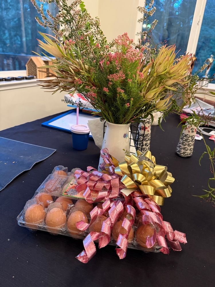 Valentine’s Day gift consisting of 24 eggs from Costco and a bouquet of flowers on a dirty table.