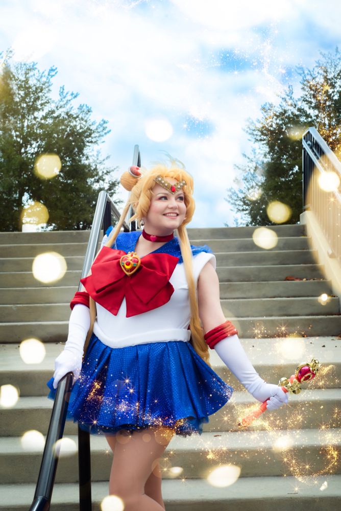 A photo of me Cosplaying Sailor Moon. I am standing on a staircase and glittery sparkly magic has been edited in. 