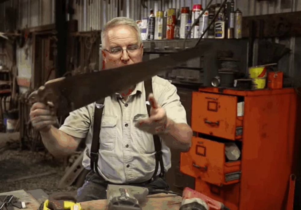 a man is holding a saw in front of an orange filing cabinet with the letter d on it