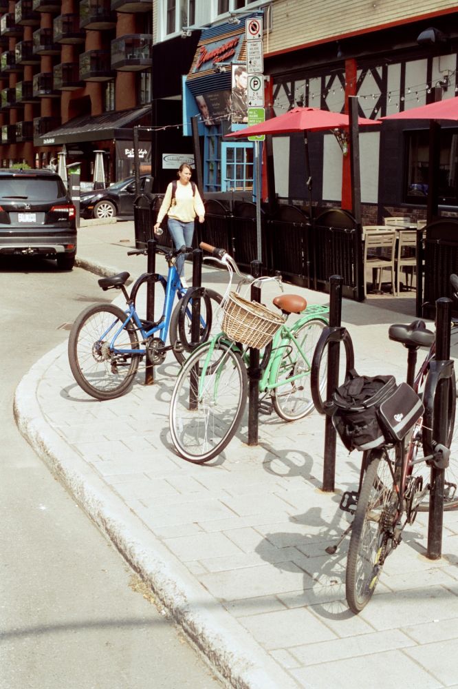 Line of bicycles locked to ring posts between a city street and pub. The focus of the photo is the bright pistachio bicycle with a wicker basket and medium brown saddle.

I make many photos of it because it's too cute and makes me want a bike again.