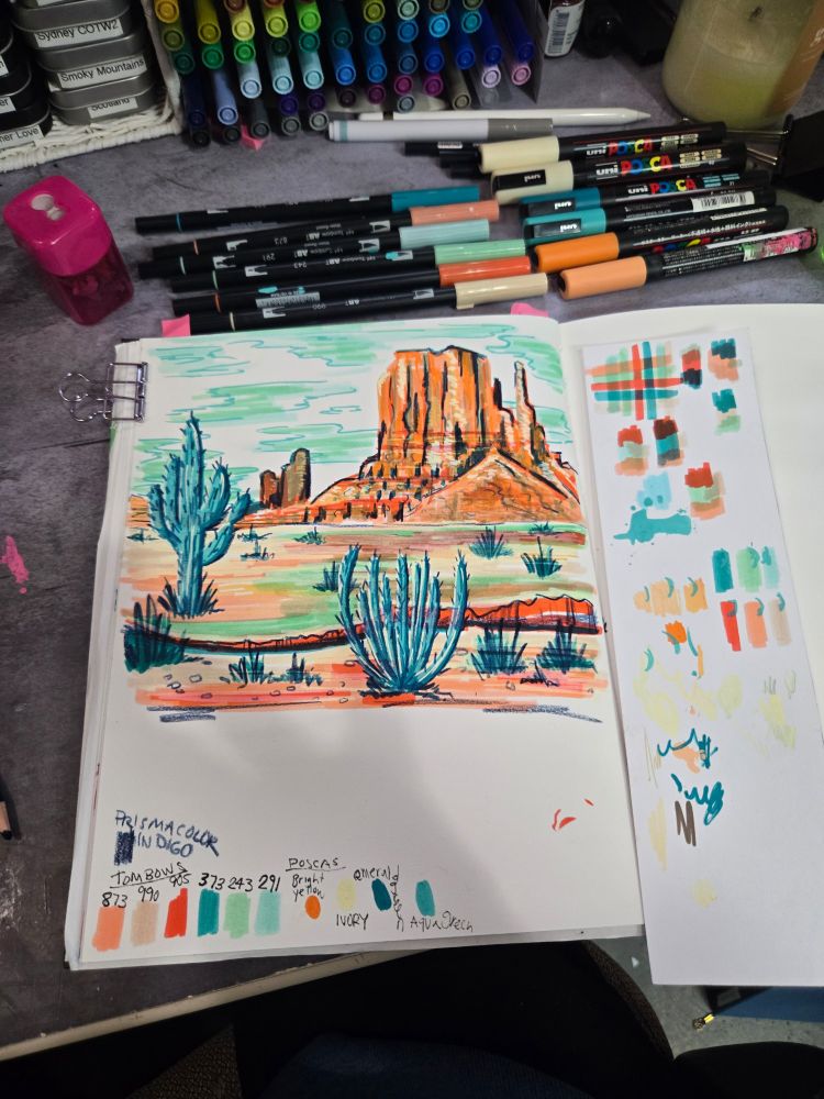 Zoomed out shot of sketchbook spread of Monument valley landscape in coral oranges and teals with Indigo colored pencil details. Includes swatches of colors and scratches pad for testing colors.