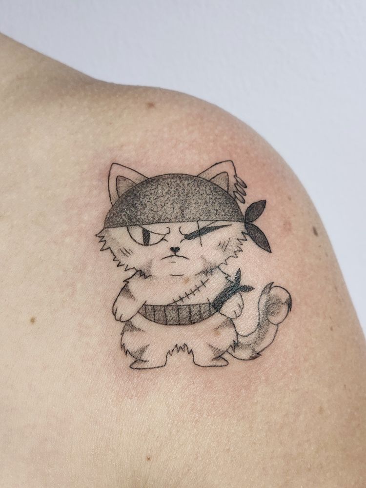 A black and grey tattoo of Roronoa Zoro as a cat on the left shoulder 