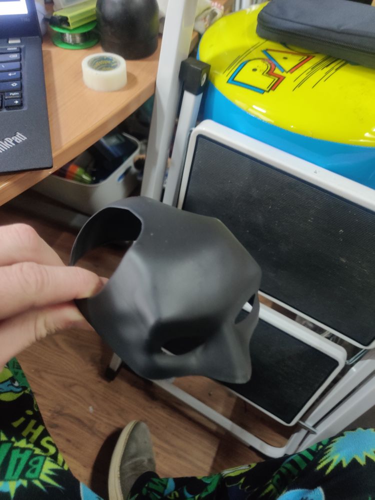 Photograph of a cat-sized Batman cowl. There are holes for the cat's ears.