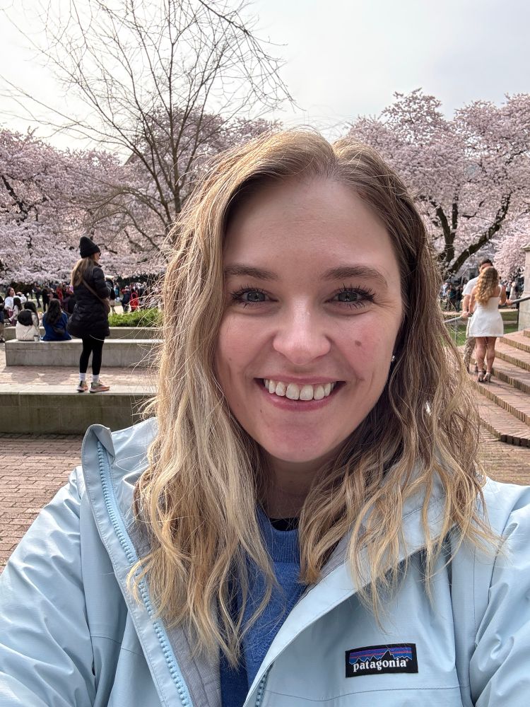 I am smiling with cherry blossom trees in the background. 