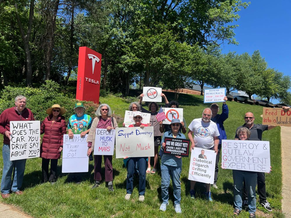 Group of protesters outside of the Silver Spring Tesla dealership for the weekly Tesla Takedown action. Signs include “Deport Musk to Mars”, “Diabolical Oligarch Grifting Efficiently”, and “Feed DOGE into a wood chipper!”