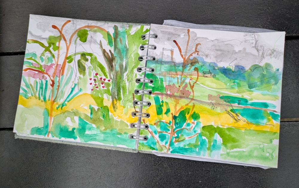 This is a photograph of a landscape shaped sketch of the view close to the river Tyne in Northumberland. The colours are mainly shades of green and yellow with some purple and pink flowers.