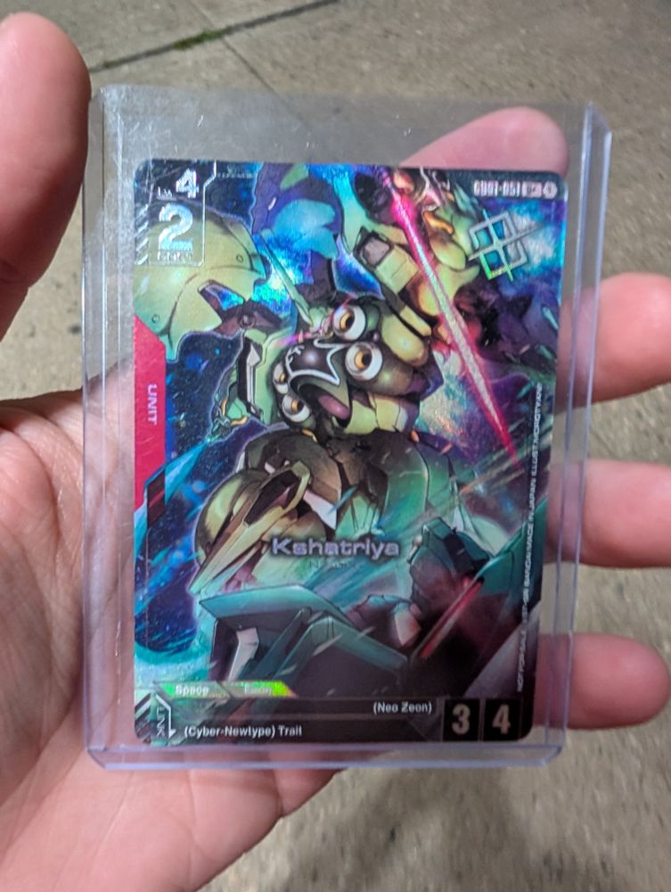 Holding a Gundam TCG Kshatriya winners promo in a top loader.