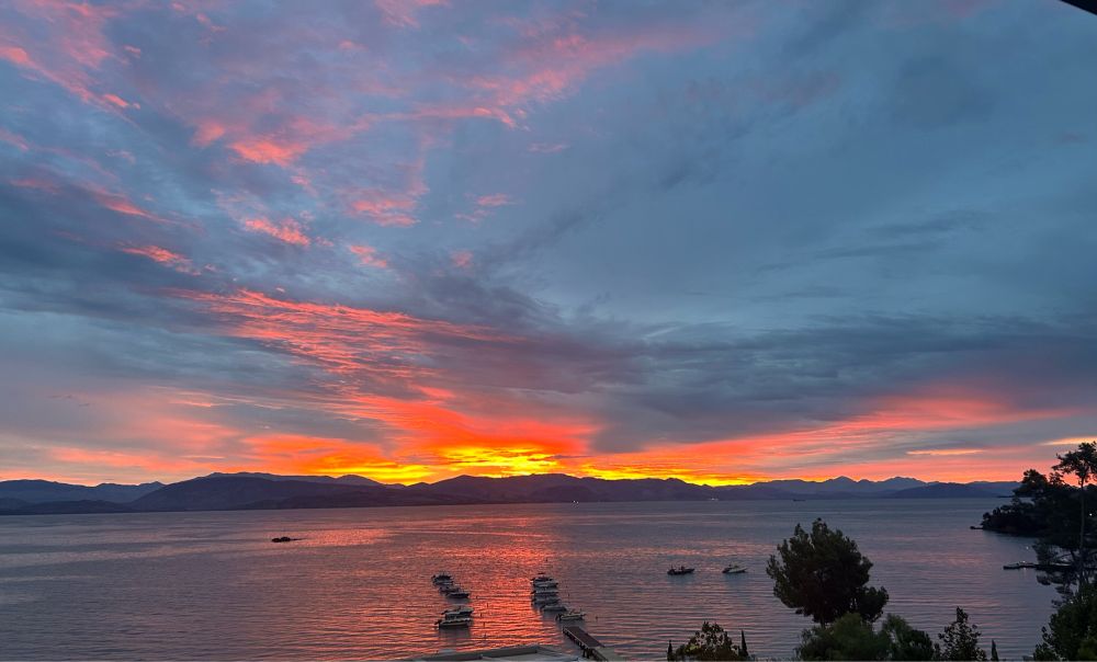 Sunrise over mountains-orange sun in a deep blue sky. Small pleasure boats in the foreground on the sea