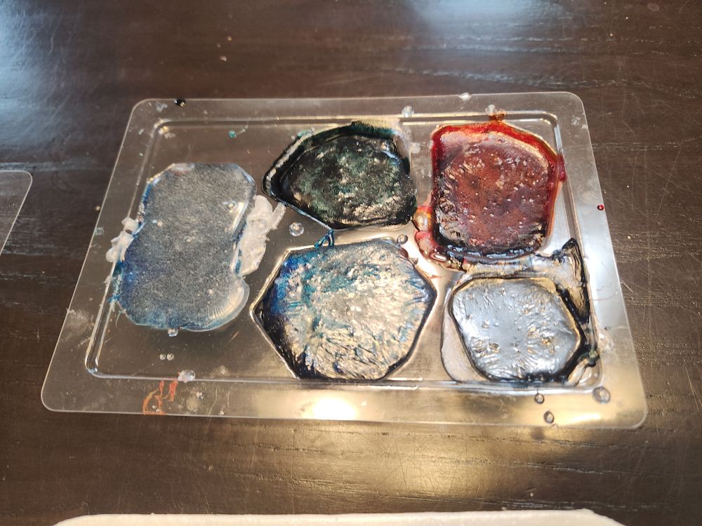 Plastic case with 5 soaps shaped as gemstones. Blue, green, red, blue, and purple - clockwise from the far left.