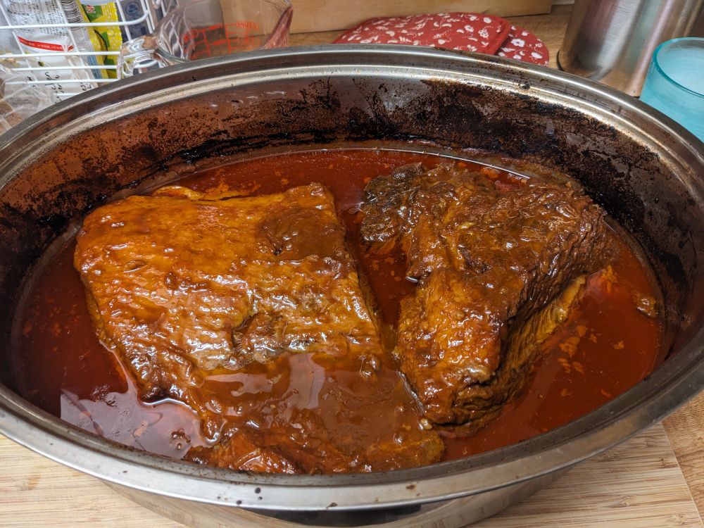 A large roasting pan with two braised briskets in it