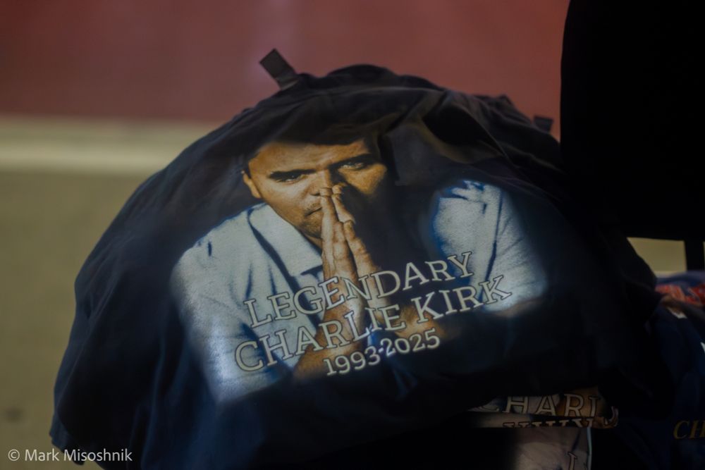 A T-shirt with a picture of Charlie Kirk praying that reads LEGENDARY CHARLIE KIRK 1993-2025