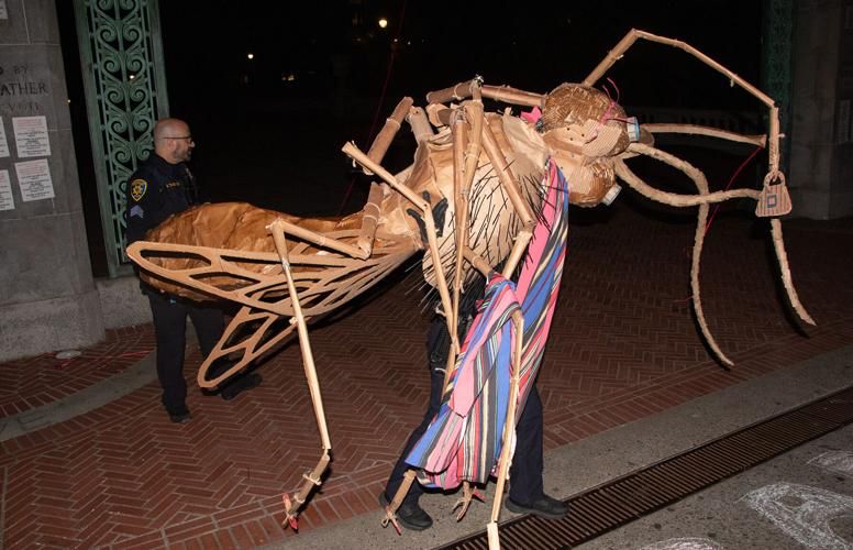 2 UCPD officers carry away a giant cardboard bug