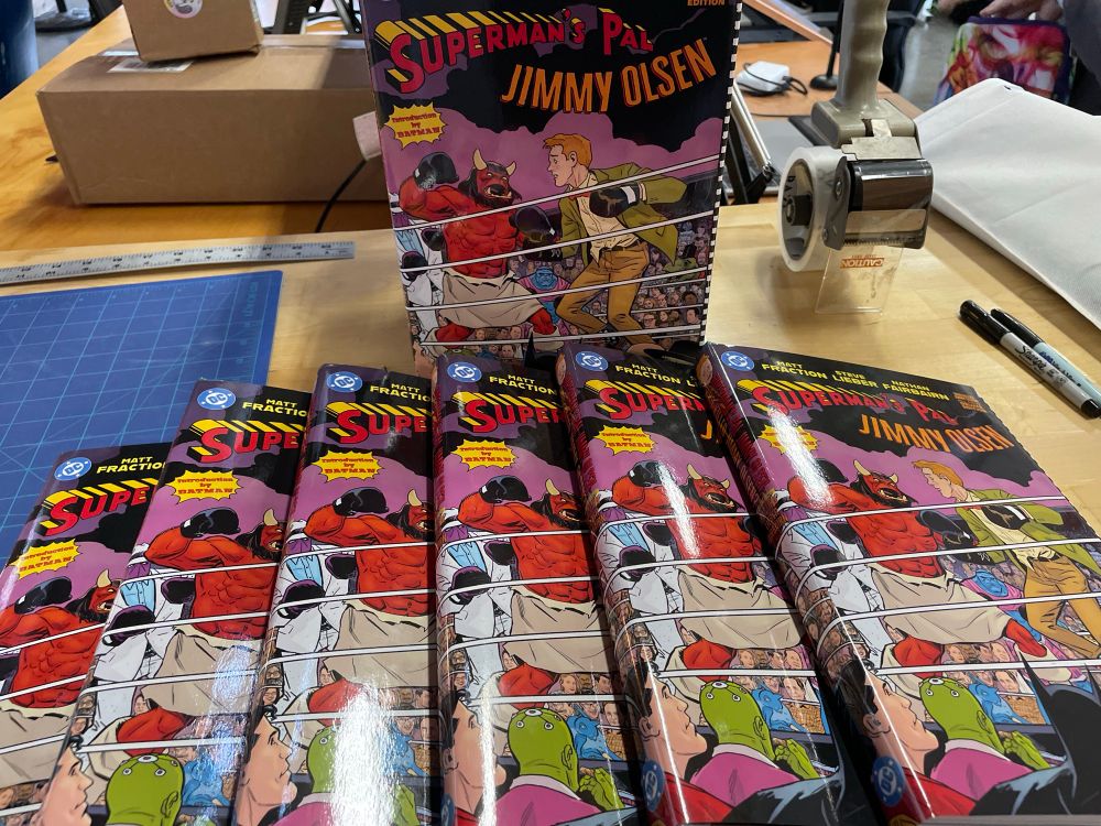 Seven copies of the Jimmy Olsen hardcover, sotting on a counter at Helioscope.