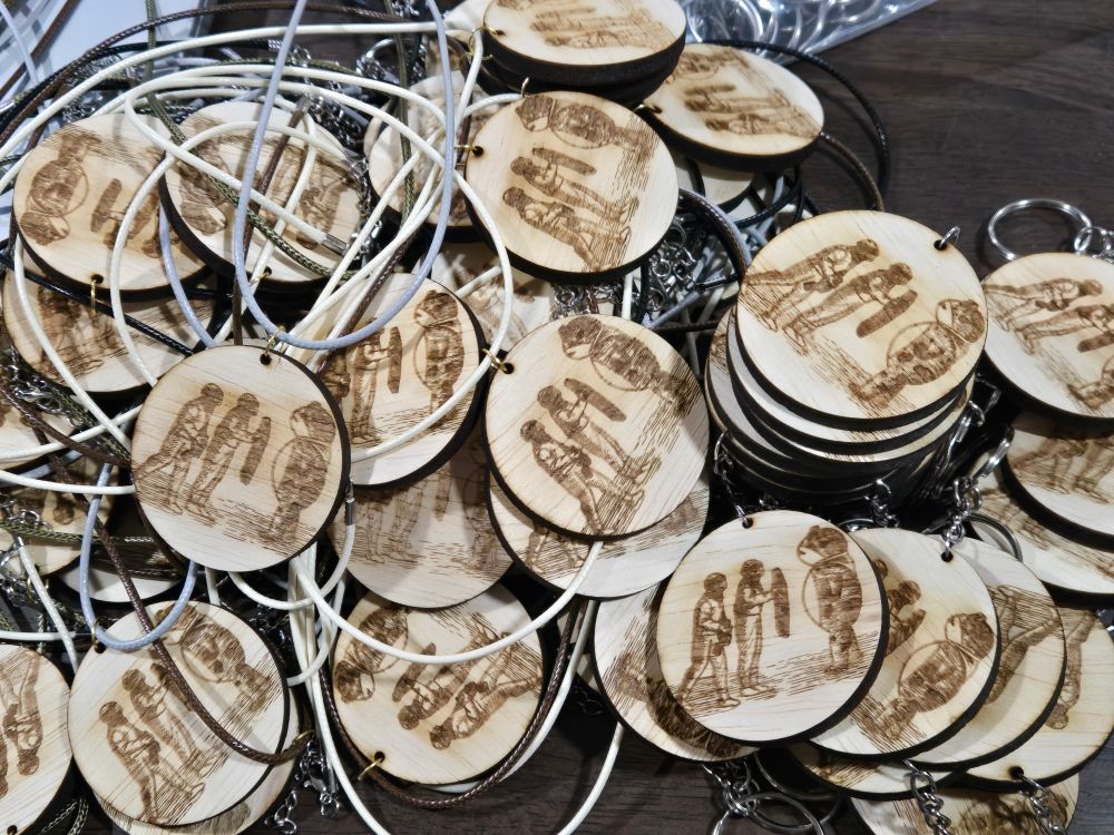 A pile of laser engraved pendants and keychains with the Frog of Portland 