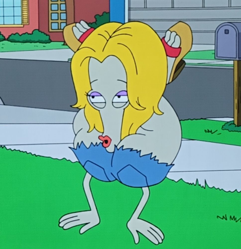 Roger from American dad walking on his arms with his legs wrapped around his neck. He’s in a blonde wig and blue eye shadow 