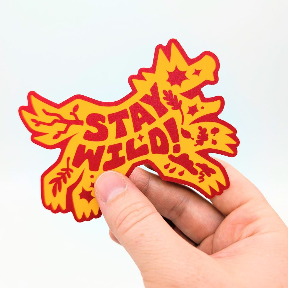 A Stay Wild sticker being held.