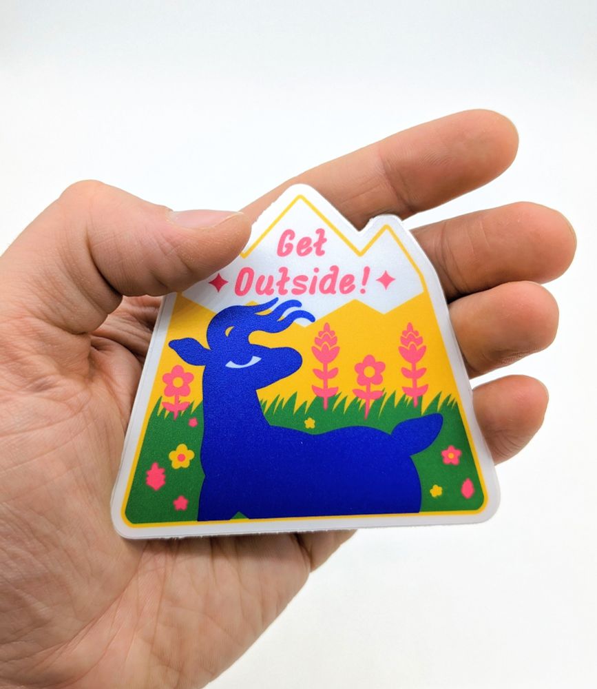A Get Outside! sticker being held.