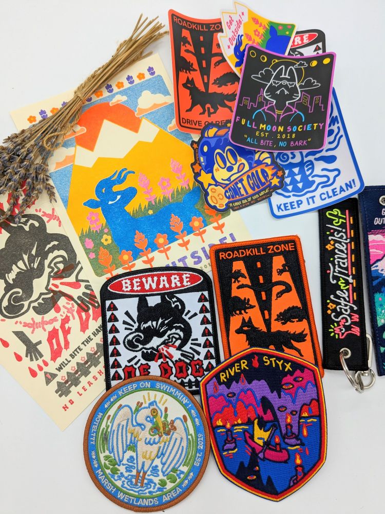 A spread of several prints, stickers, patches & keychains in the MOTEL777 shop.