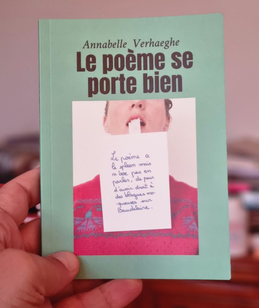 Couverture du livre Le poème se porte bien de Annabelle Verhaeghe Bout de papier tenu par la langue d'une personne, sur lequel est écrit : Le poème à le spleen mais n'ose pas en parler de peur d'avoir droit à des blagues moqueuses sur Baudelaire.
