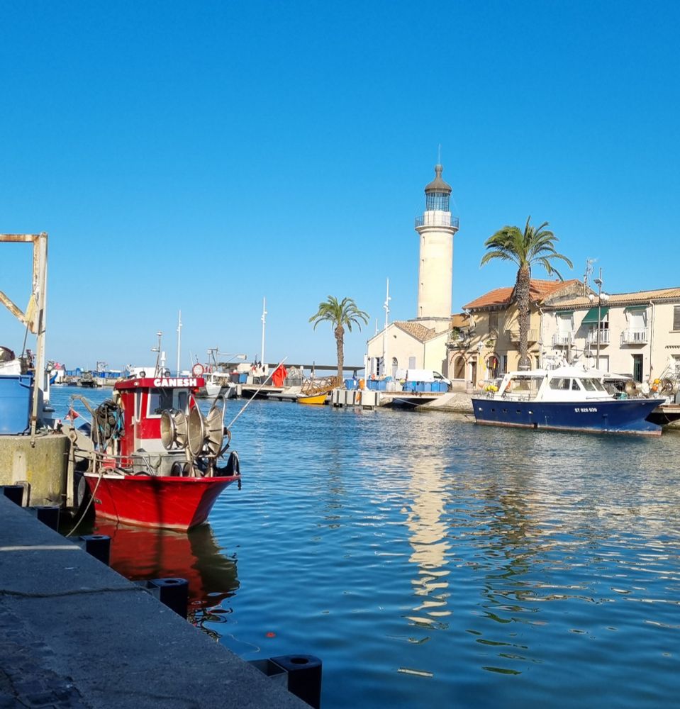 Phare du Grau du roi au bout du canal.
Petit bateau de pêcheur à gauche.