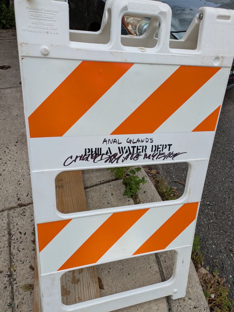 A Phila Water Dept sandwich board on which someone has written "ANAL GLANDS"