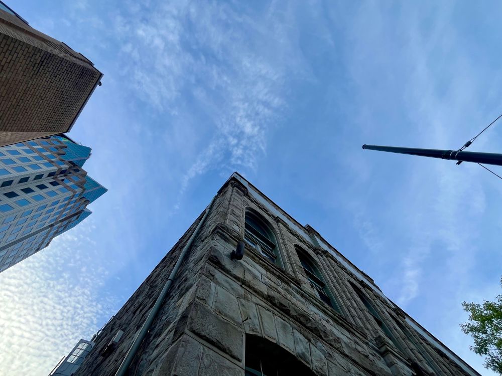 Wide angle shot upwards of the Z-Space building at 505 Hamilton with a blue sky streaked with cloud and sun. 