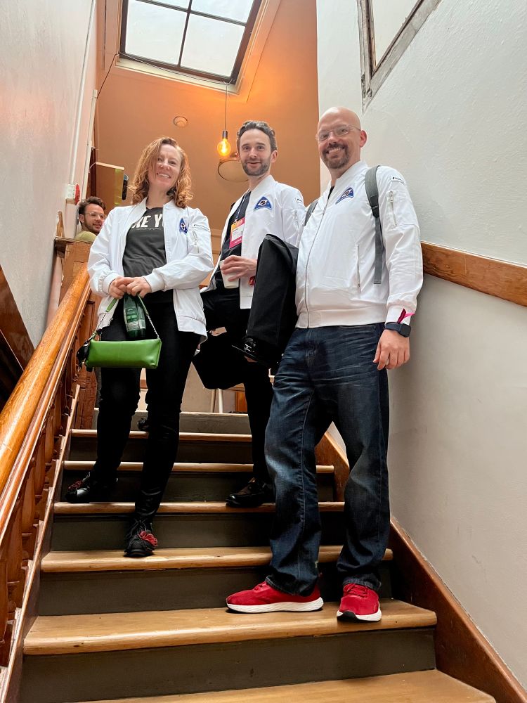 Matching white jackets with launch badges standing on the stairs at Z-Space 