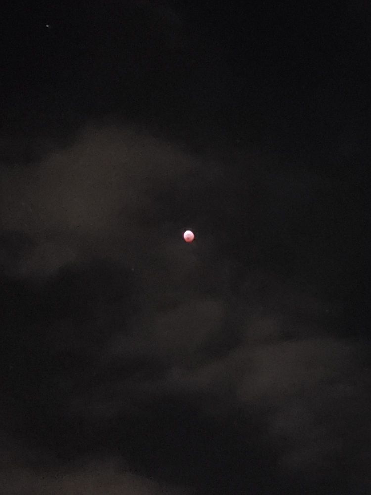 closer shot of lunar eclipse behind clouds