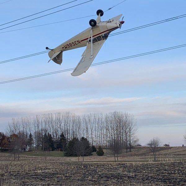 A small plane is tangled upside-down in power lines. 